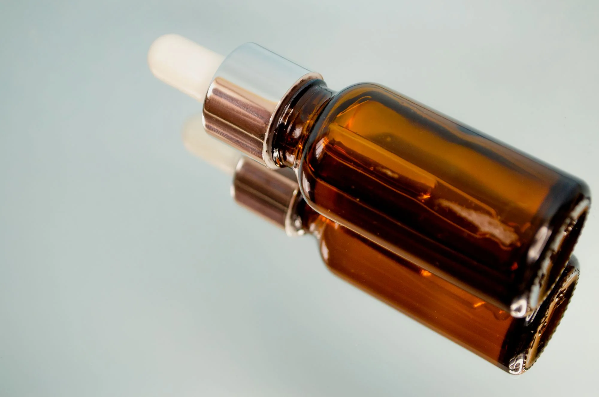 Close-up of a brown dropper bottle reflecting on a glass surface, perfect for skincare or aromatherapy themes. Editorial photograph for our Balancing Oil Essence guide for Dubai shoppers.