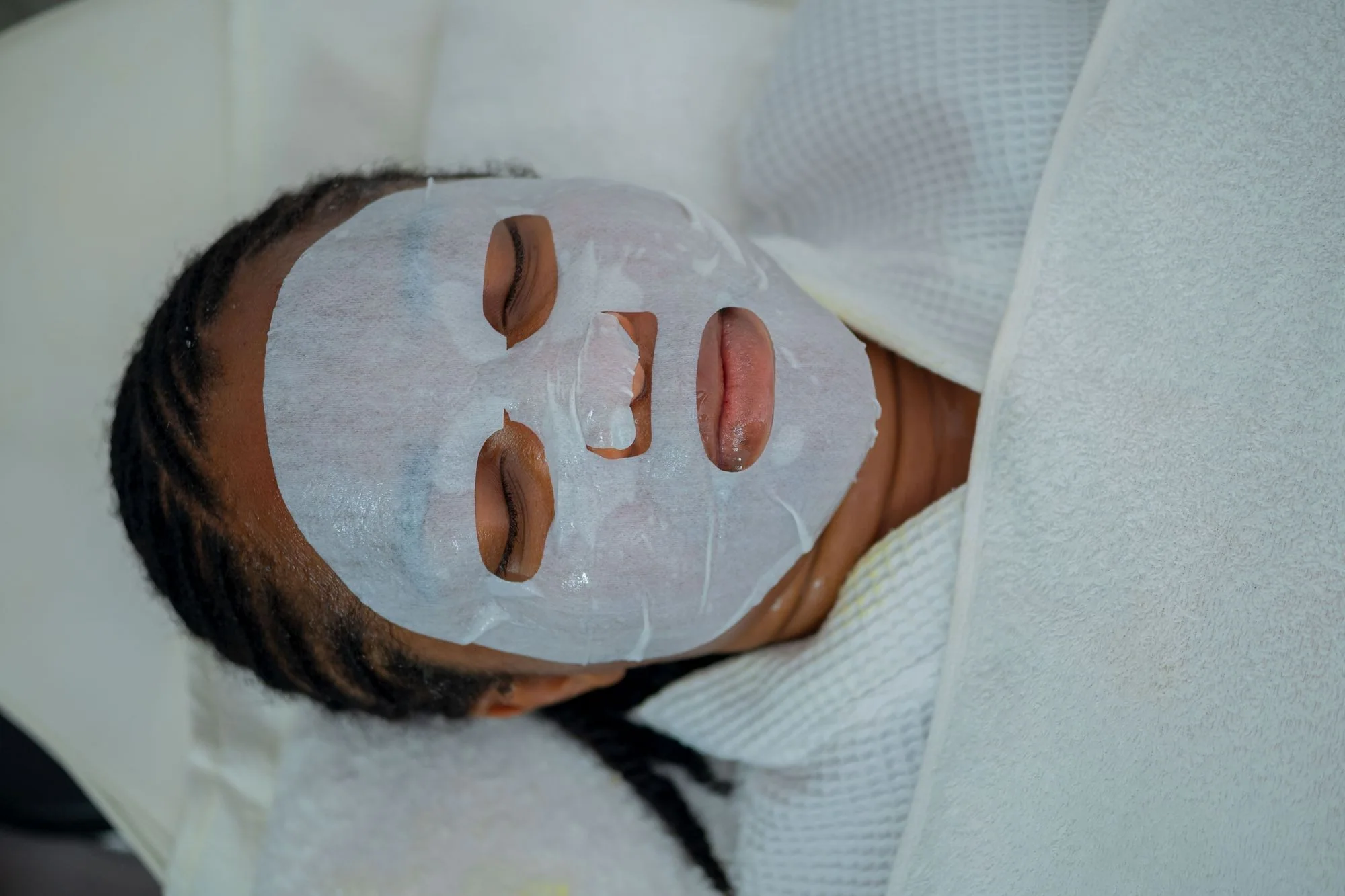 Woman enjoying a rejuvenating facial mask treatment at a spa in Abuja, Nigeria. Editorial photograph for our Smooth Mask guide for Dubai shoppers.