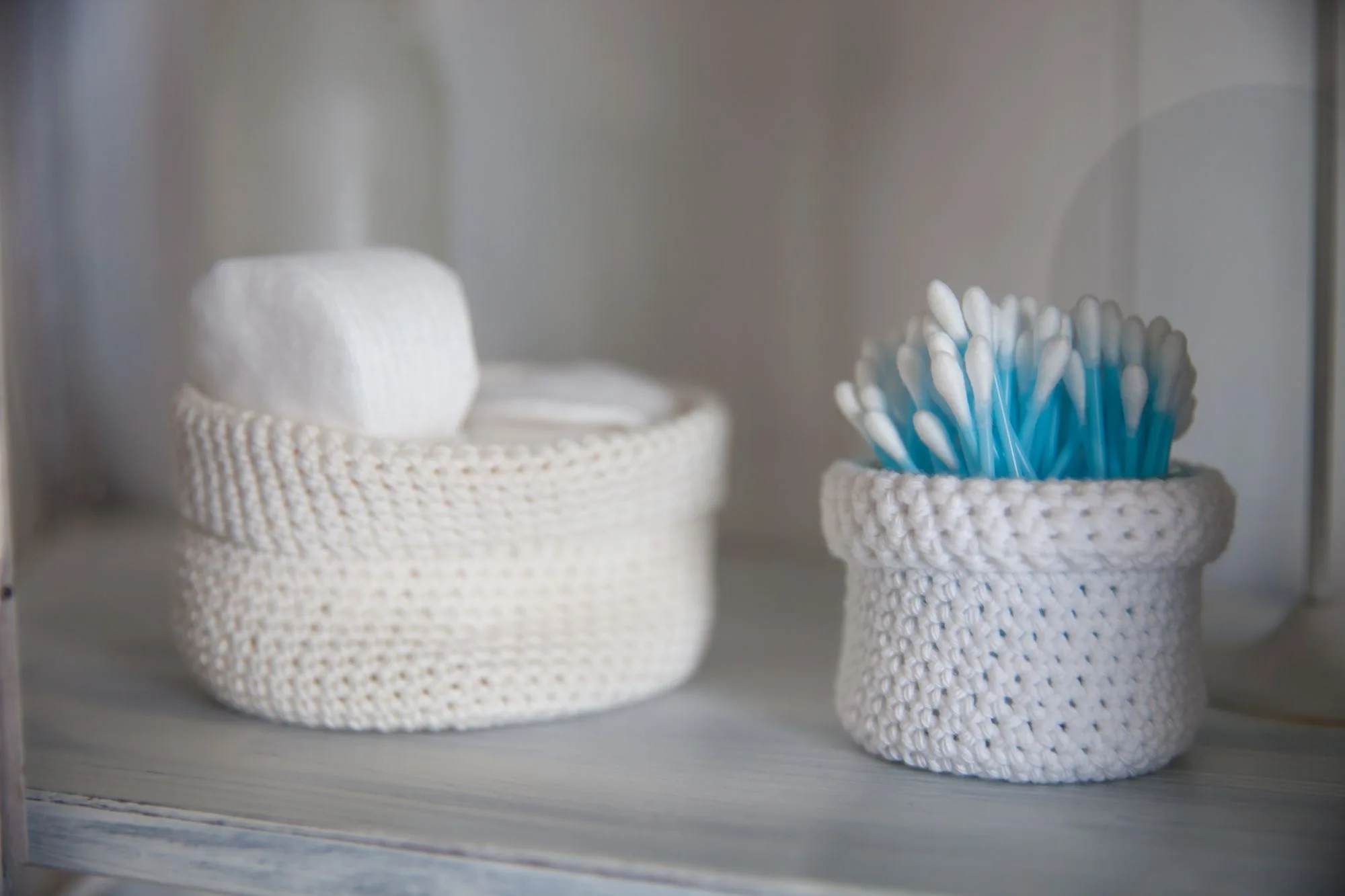 A close-up of cotton swabs and pads in crocheted baskets, creating a soft, neutral, and cozy bathroom atmosphere. Editorial photograph for our skincare shelf guide for Dubai shoppers.