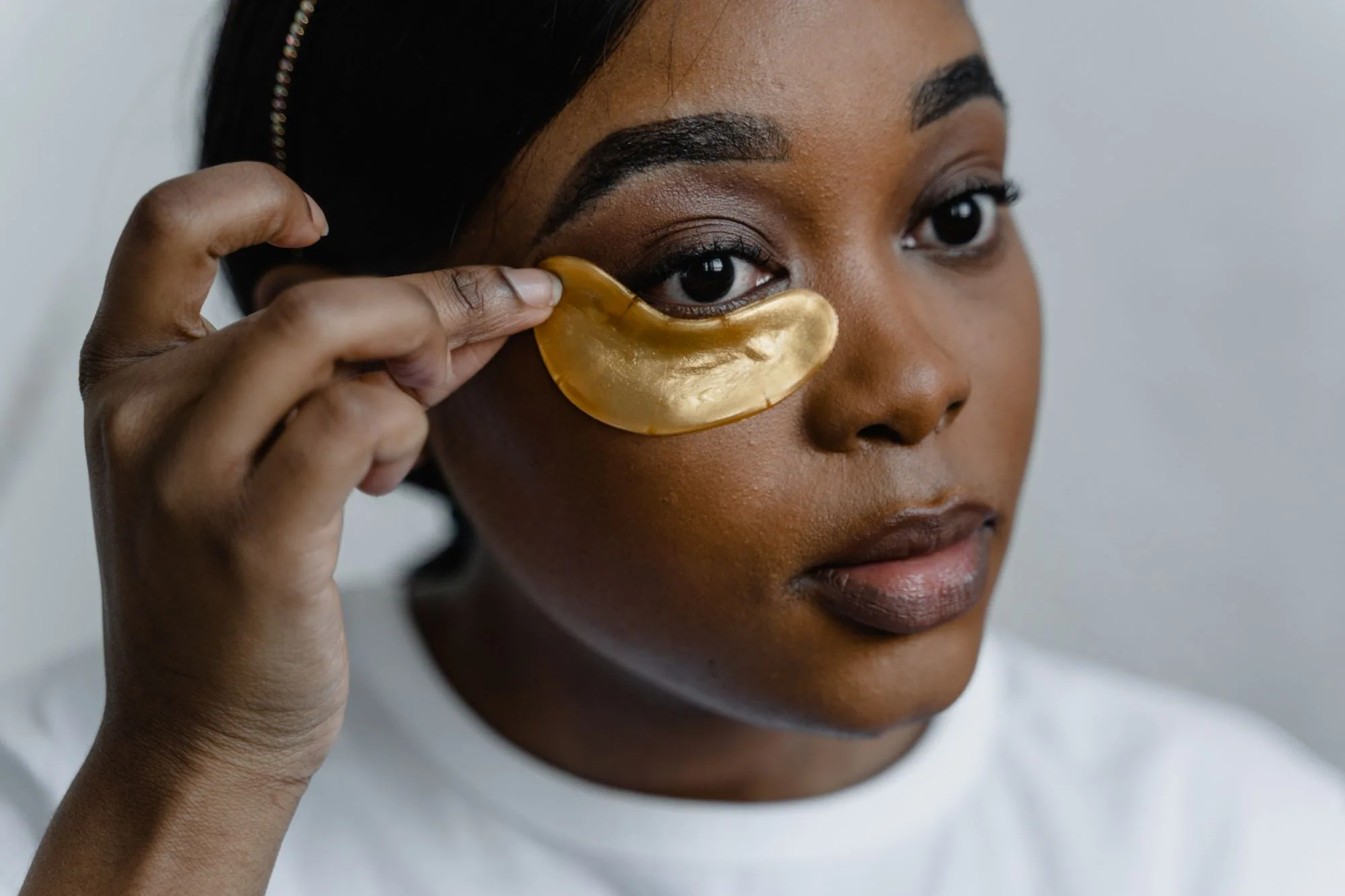 Close-up of a woman applying gold eye patches for skincare routine. Editorial photograph for our eye care guide for Dubai shoppers.