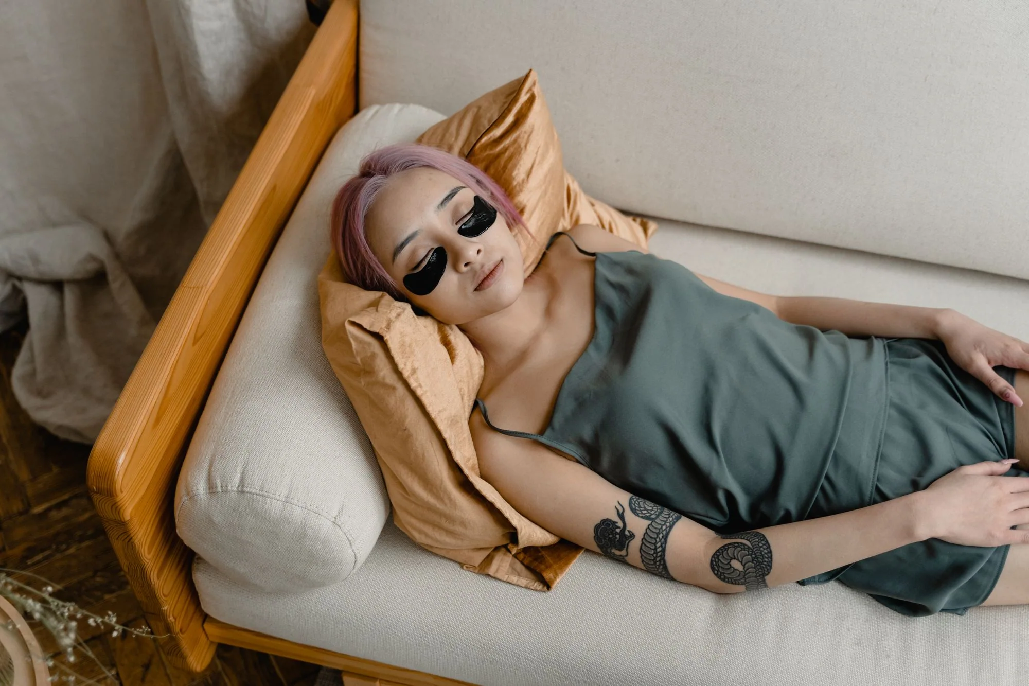Asian woman with pink hair relaxing with eye patches for skincare routine. Editorial photograph for our sheet-mask guide for Dubai shoppers.