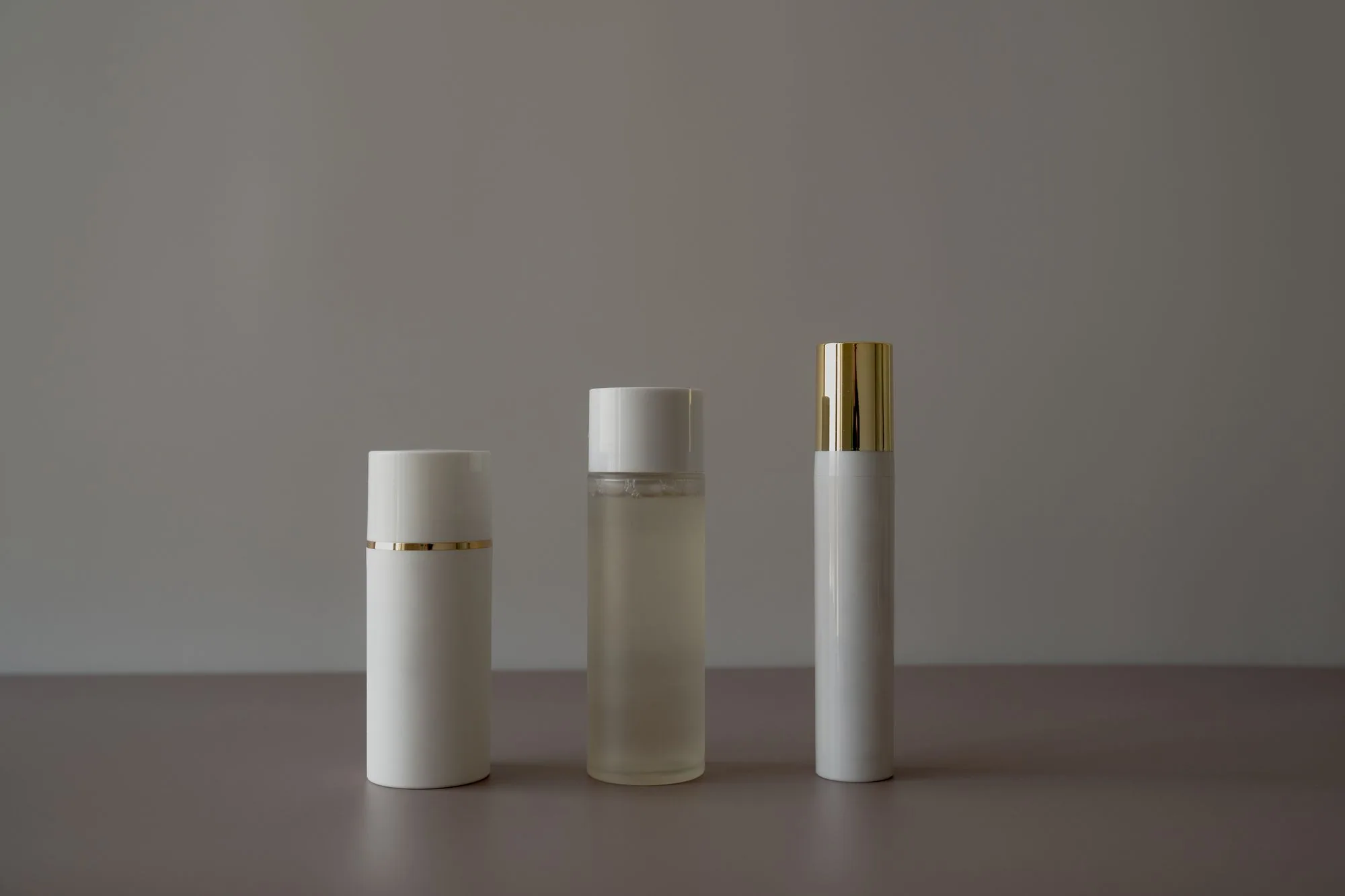 Simple minimalist arrangement of cosmetic bottles on a gray background. Editorial photograph for our skincare review guide for Dubai shoppers.