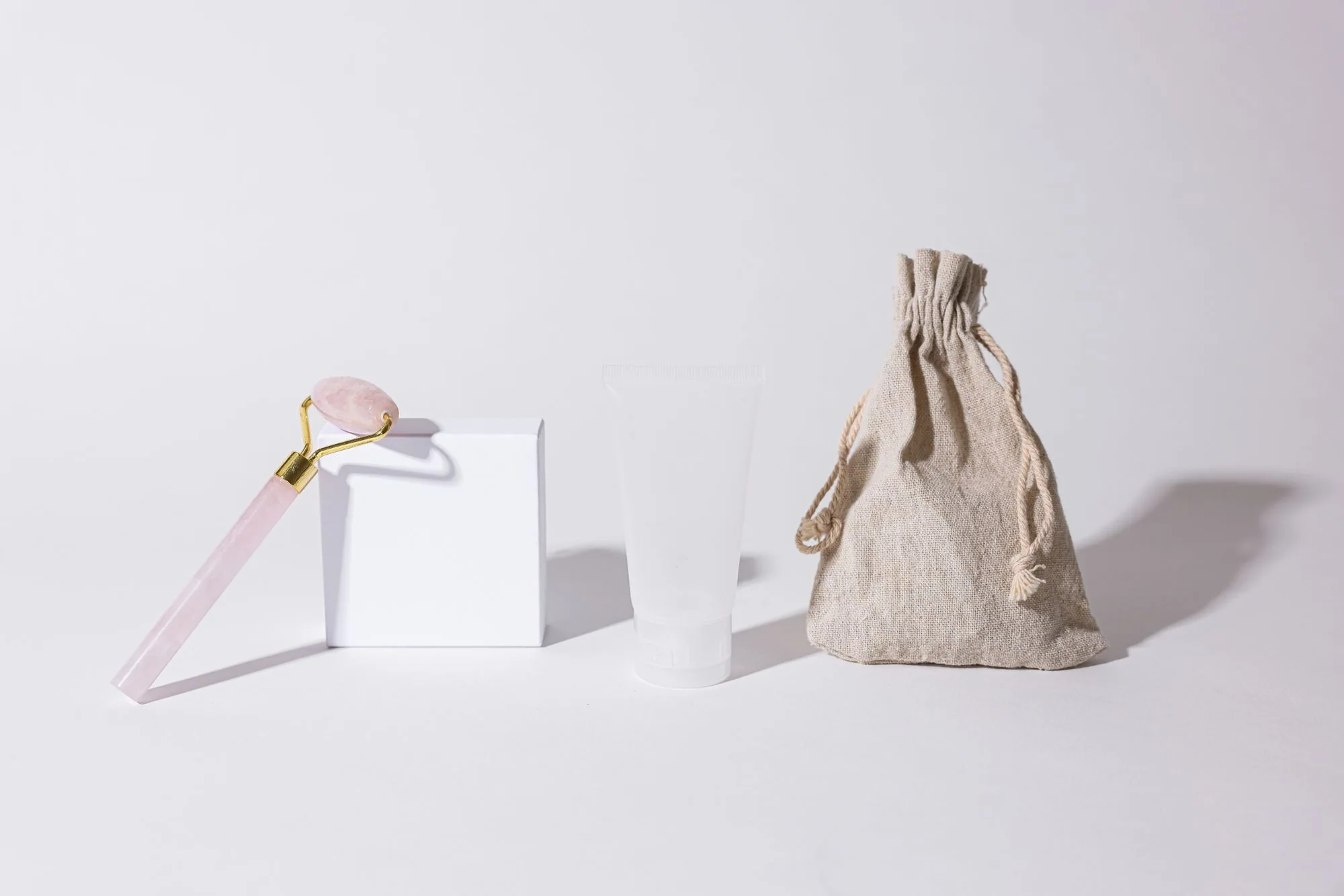 Cosmetic set with rose quartz roller and neutral packaging on white background. Editorial photograph for our fragrance guide for Dubai shoppers.