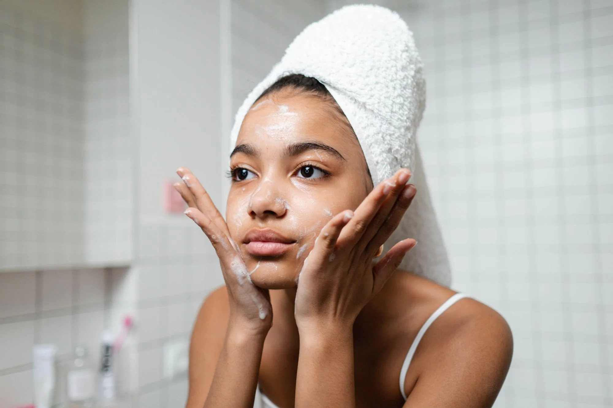 Young woman practicing skincare routine with a towel wrap indoors. Editorial photograph for our Clear Wash Foam guide for Dubai shoppers.