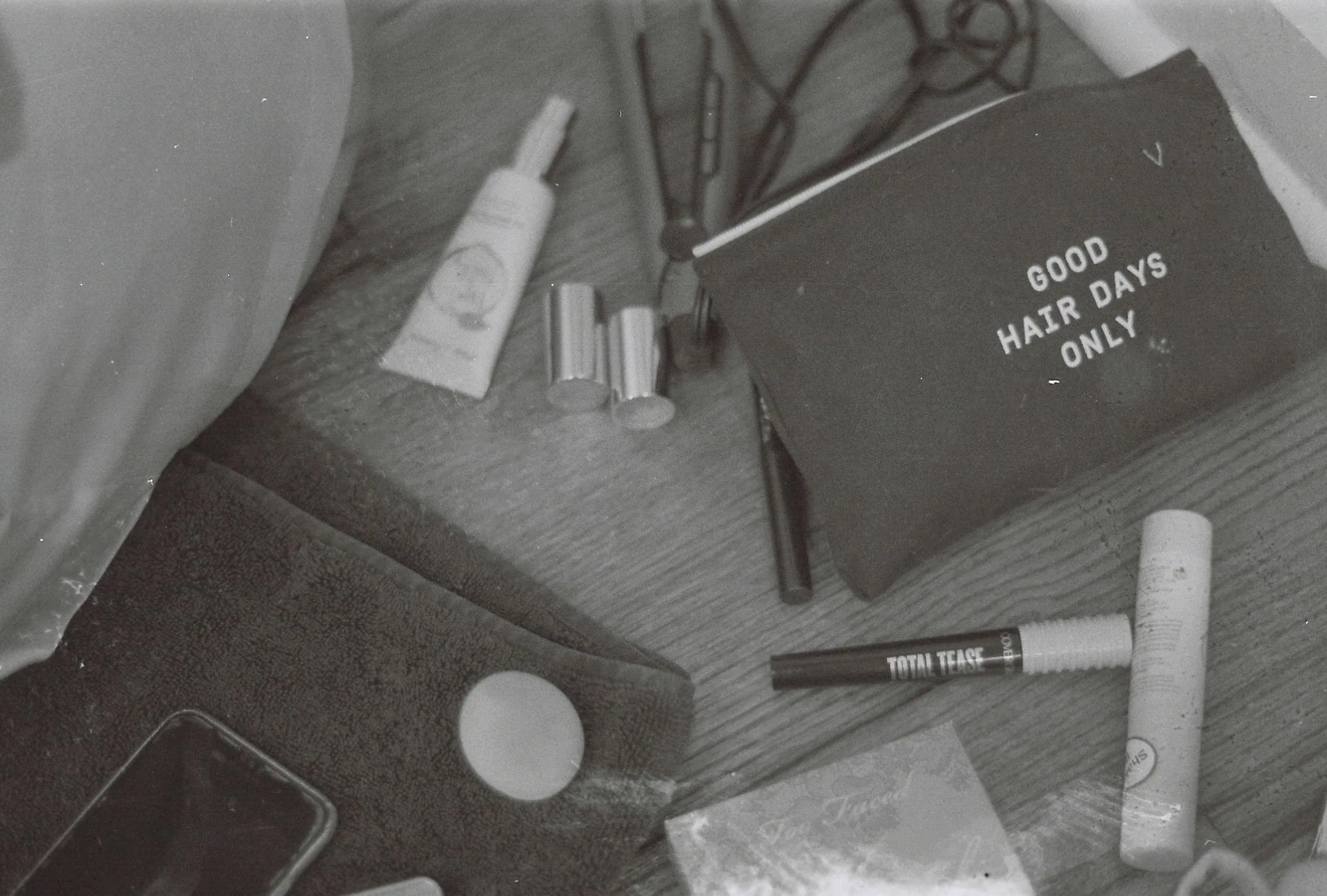 Flat lay of cosmetics and hair essentials on a wooden surface in monochrome. Editorial photograph for our skincare for travel guide for Dubai shoppers.